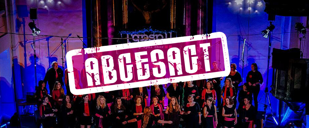 Der Grazer Gospelchor steht im Mittelpunkt der Bühne auf einer schwach beleuchteten Plattform, leuchtende Lichter tanzen um ihn herum, während die auffällige Grafik „ABCESACT“ über der fesselnden Darbietung schwebt.
